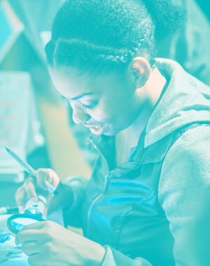 Person smiles and looks closely at a piece with a magnifying glass.